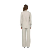 A woman wears the back of a beige Jacqueline De Yong women grey linen v neck loose shirt with subtle pleats