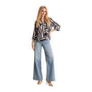 Une femme porte un haut Jacqueline de Yong bleu en viscose à col en V top avec des manches 3/4 associées à un pantalon évasé en denim clair