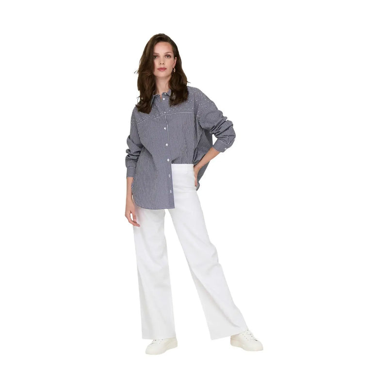 Une femme porte un pantalon en coton blanc Jacqueline de Yong taille 30 avec une chemise boutonnée à rayures bleu marine et blanches.