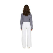 Une femme porte un pantalon blanc en coton taille haute à jambes larges de la marque Jacqueline de Yong, taille 30, avec une chemise à rayures bleu marine.