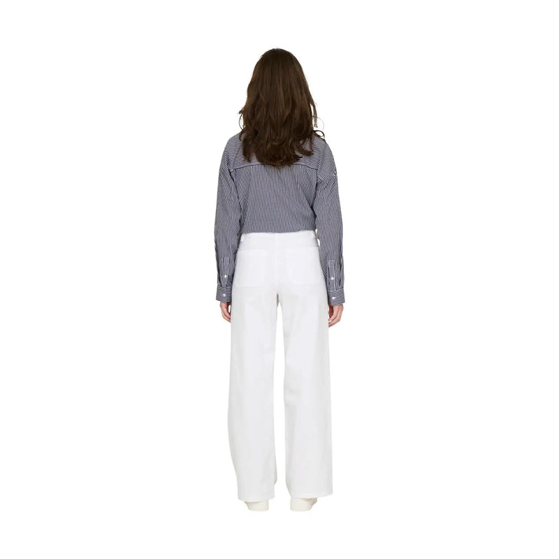 Une femme porte un pantalon blanc en coton taille haute à jambes larges de la marque Jacqueline de Yong, taille 30, avec une chemise à rayures bleu marine.