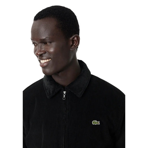 Blazer Lacoste pour homme en coton, en velours côtelé noir, fermeture éclair, col foncé contrastant et logo crocodile vert sur la poitrine.