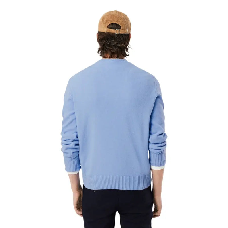 Pull Lacoste pour homme, en maille bleu clair, col rond, en laine, poignets et ourlet côtelés, assorti à un bonnet en velours côtelé beige.