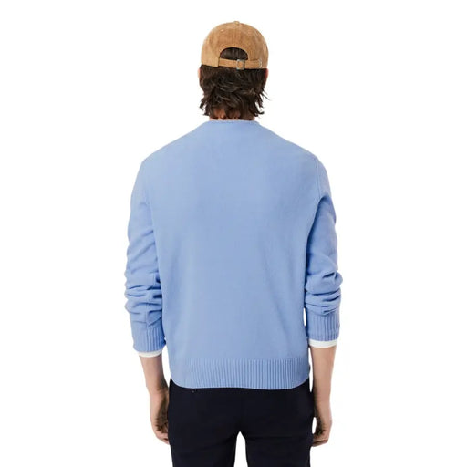 Pull Lacoste pour homme, en maille bleu clair, col rond, en laine, poignets et ourlet côtelés, assorti à un bonnet en velours côtelé beige.