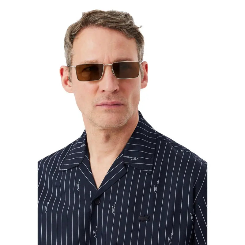 Chemise Lacoste pour homme, associée à des lunettes de soleil rectangulaires à verres bruns et monture métallique.