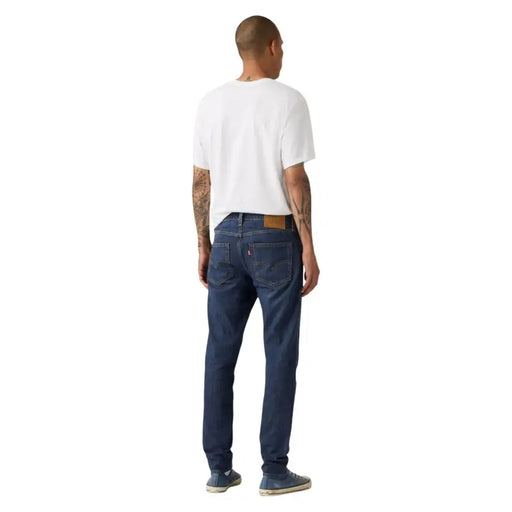 Arrière d'un jean Levi's bleu foncé pour homme, en coton et lin, avec une coupe classique à cinq poches et un empiècement en cuir marron.