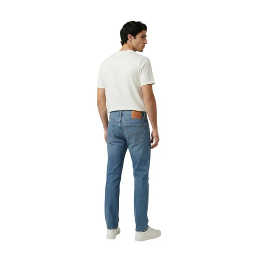 Vue arrière d'un jean Levi's pour homme en denim bleu, coton stretch, coupe slim classique, avec un empiècement en cuir marron à la ceinture.