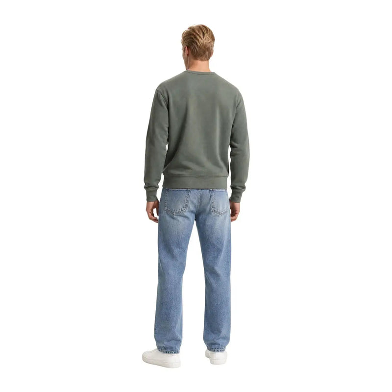 Un homme portant un sweat-shirt Levi's vert en coton à col rond, associé à un jean bleu clair.