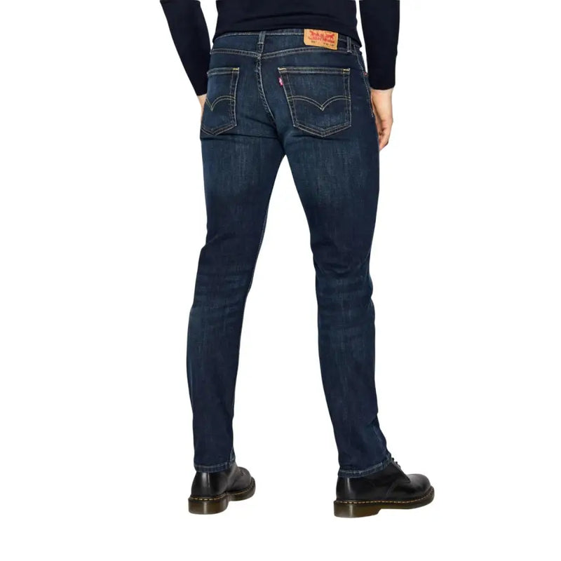 Vue arrière d'un jean Levi's pour homme, coupe classique, en denim indigo foncé, coton stretch bleu, cinq poches et étiquette en cuir rouge.