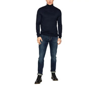 Un homme portant un jean Levi's bleu en coton stretch coupe classique 04511-1390, associé à un pull à col roulé bleu marine