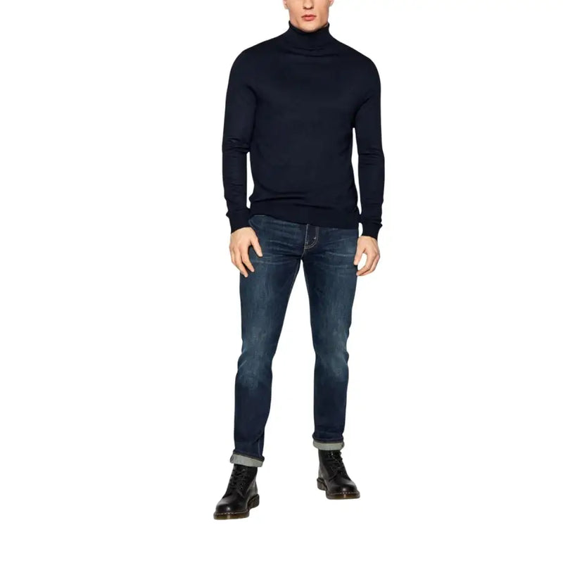 Un homme portant un jean Levi's bleu en coton stretch coupe classique 04511-1390, associé à un pull à col roulé bleu marine