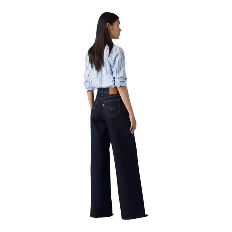 Arrière d'un jean Levi's pour femme en mélange de coton noir, coupe large, en denim indigo foncé, avec logo classique et passant de ceinture marron.