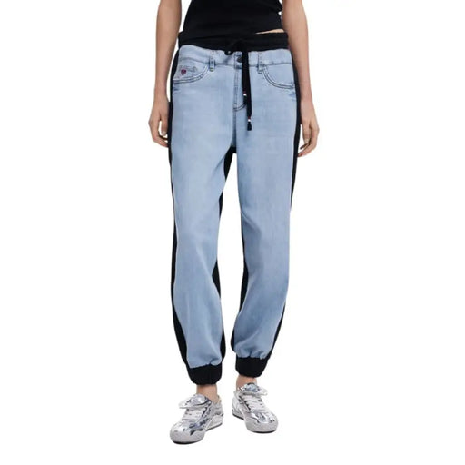 Light blue denim jogger pants with black side stripes displayed in a product image