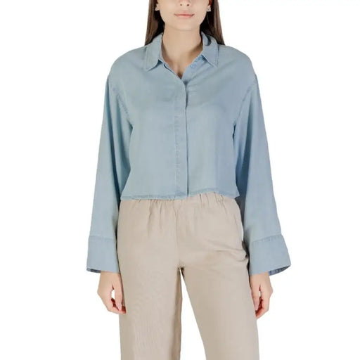 Light blue long-sleeved shirt paired with beige pants displayed in the Blue Denim Cropped Shirt product image