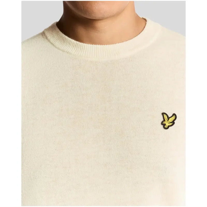 Cream-colored crew neck sweater with a small yellow bird emblem on the left chest.