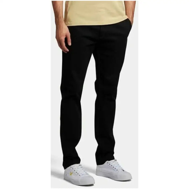 Lyle & Scott Pantalon slim noir pour homme en mélange de coton avec logo doré discret, porté avec des baskets blanches