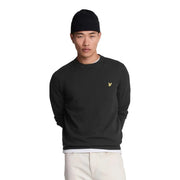 Lyle & Scott Pull en laine mérinos noire pour homme, orné d'un logo oiseau doré sur la poitrine gauche (vue de face).