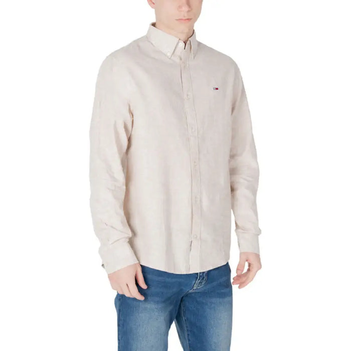 Man wearing a beige long-sleeved button-down shirt and blue jeans