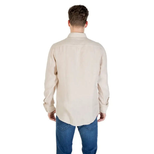 Man wearing a beige long-sleeved button down shirt and blue jeans