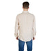 Man wearing a beige long-sleeved button down shirt and blue jeans