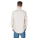Man wearing a beige long-sleeved button-down shirt and blue jeans