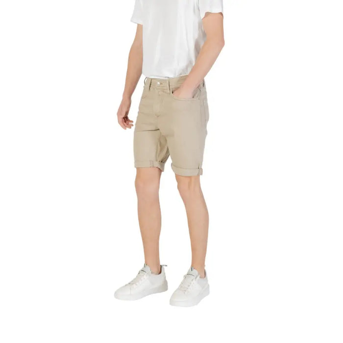 Man wearing beige chino shorts and white sneakers displaying a casual summer outfit
