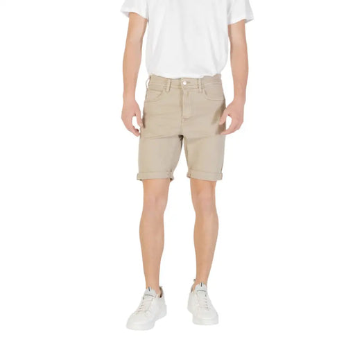 Man wearing beige chino shorts and white sneakers showcasing casual summer style