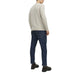 Man wearing a beige crew neck sweater and dark blue jeans displayed in the product listing