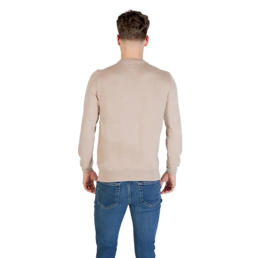 Man wearing beige long-sleeved sweater and blue jeans for the product listing