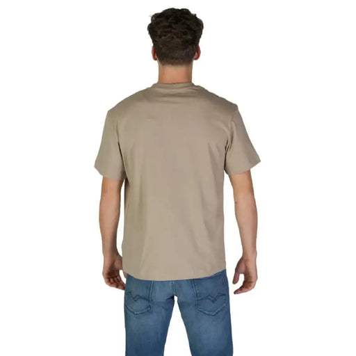Man wearing a beige Replay Logo T Shirt and blue jeans, showcasing casual style