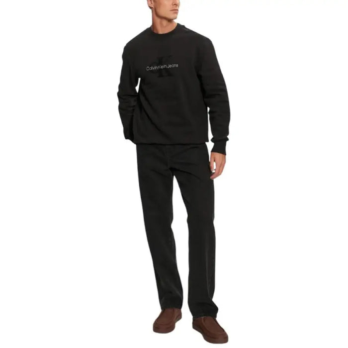 Man in black Calvin Klein sweatshirt and pants showcasing Calvin Klein Jeans product