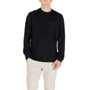 Man wearing a black long-sleeved shirt and light-colored pants showcasing casual style