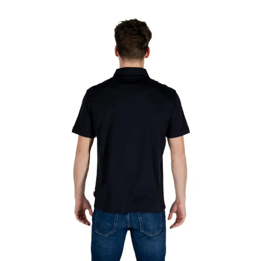 Man wearing Armani Exchange black polo shirt and blue jeans in stylish casual look