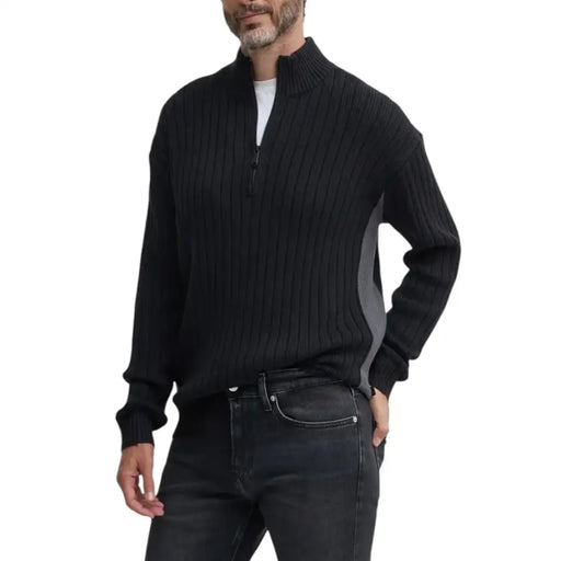 Man wearing black ribbed knit quarter-zip sweater and dark jeans displayed in product listing