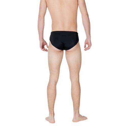 Man in black swim briefs showcasing Ea7 Men’s Black Plain Slip On Swimwear for Spring Summer
