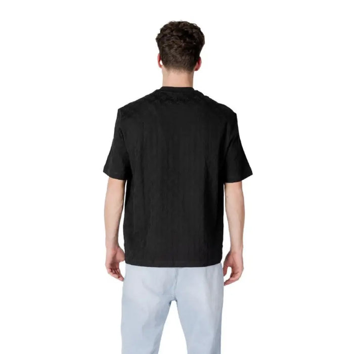 Man wearing a black t-shirt and light blue pants showcasing Armani Exchange Men Black Cotton T-Shirt