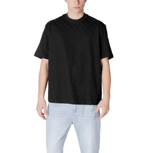 Man in black Armani Exchange round neck t-shirt and light blue jeans