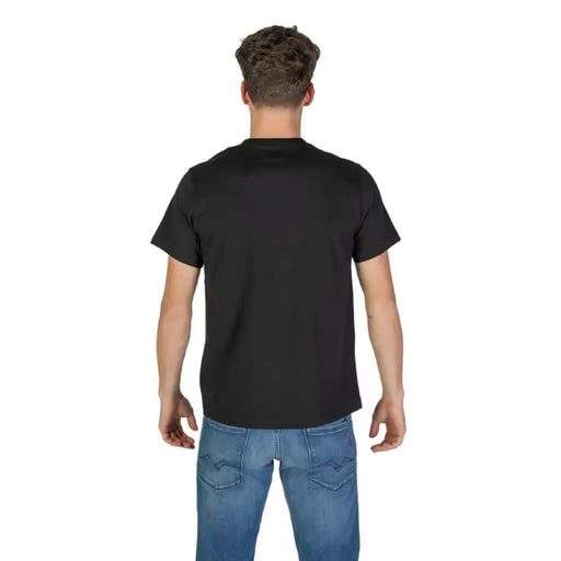 Man wearing black T-shirt with floral pocket and blue jeans in a styled product display
