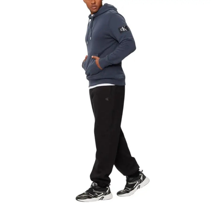 Man in blue hoodie and black sweatpants from Calvin Klein Jeans Men’s Trousers collection