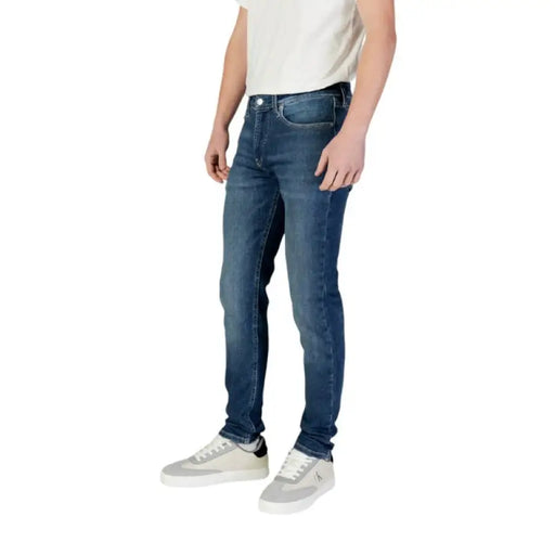 Man in Calvin Klein Men’s Blue Jeans with sneakers, showcasing casual style