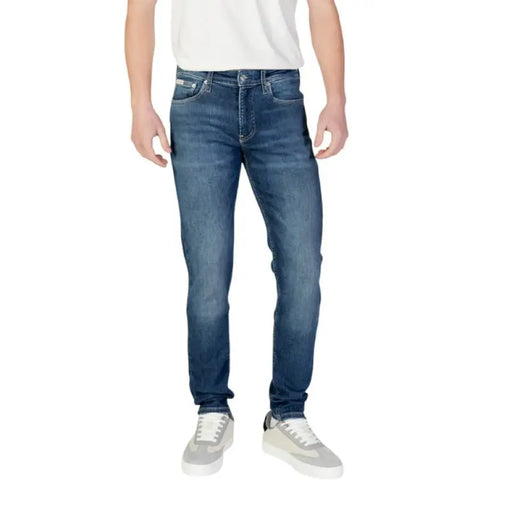 Man showcasing Calvin Klein Men’s Blue Jeans paired with gray sneakers