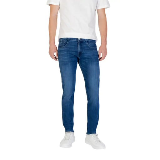 Man wearing blue denim jeans and a white t-shirt in a product display of Blue Denim Jeans and White Sneakers