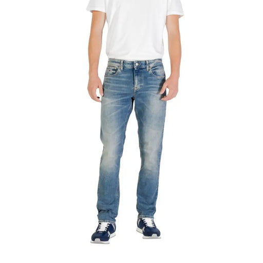 Man wearing light blue jeans and blue sneakers showcasing men’s fashion