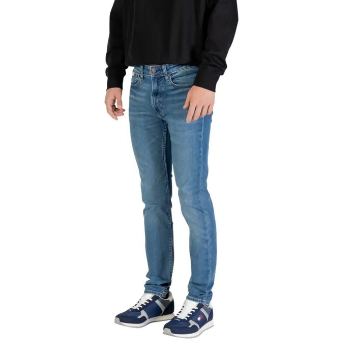 Man wearing light blue denim jeans and sneakers standing confidently