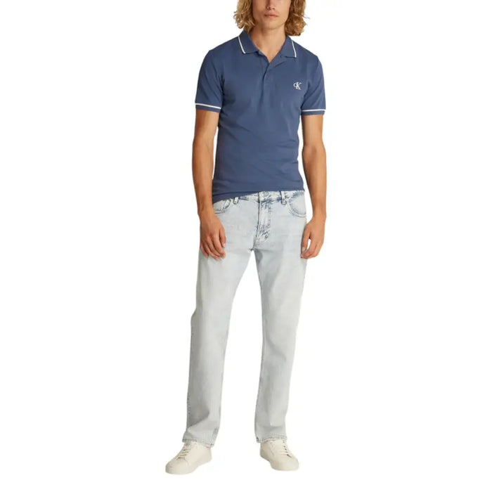 Man wearing a blue polo shirt with white trim and light-wash jeans
