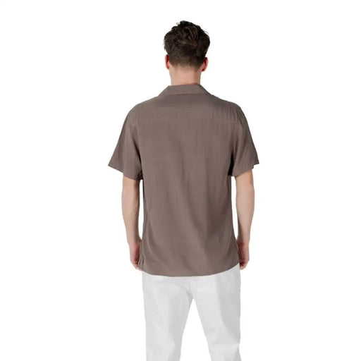 Man wearing a brown short-sleeved button-down shirt and white pants