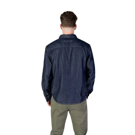 Man in dark blue Calvin Klein button-down shirt with front pockets and green pants