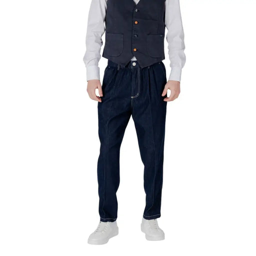 Man wearing dark blue vest and loose pants with white stitching showcasing stylish menswear