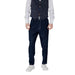 Man wearing dark blue vest and loose pants with white stitching showcasing stylish menswear