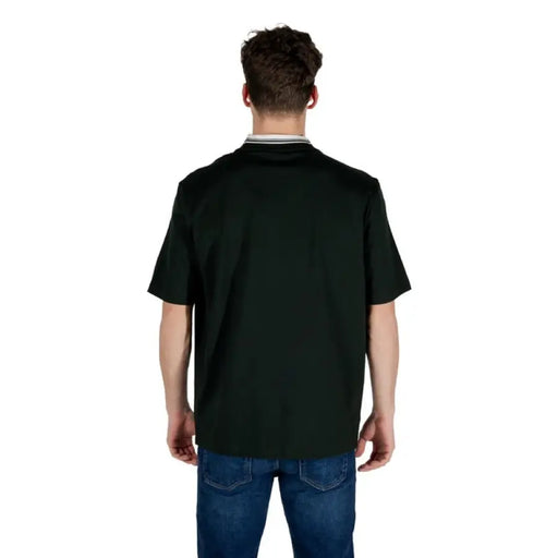 Man in dark green short-sleeved shirt and blue jeans showcasing Armani Exchange T Shirt